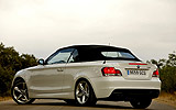 BMW Serie 1 Cabrio. Modelo 2009. Imagen. Posterior lateral. Coche parado. Carretera. Alpinweiss. Llanta 18 pulgadas 5 radios Estrella.