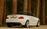 BMW Serie 1 Cabrio. Modelo 2009. Imagen. Posterior lateral. Coche parado. Carretera. Alpinweiss. Llanta 18 pulgadas 5 radios Estrella.