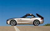 BMW Z4. Modelo 2009. Imagen exterior. Lateral. Coche parado. Proceso de apertura del techo duro plegable. Carretera.