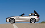 BMW Z4. Modelo 2009. Imagen exterior. Lateral. Coche parado. Proceso de apertura del techo duro plegable. Carretera.