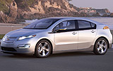 Chevrolet Volt. Modelo 2011. Imagen. Exterior. Lateral frontal. Coche parado. Carretera. Intermitentes en on. Gris.