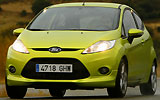 Ford Fiesta. Modelo 2009. Imagen. Frontal lateral. Coche en movimiento. Luces faros en on. Carretera. Color verde squeeze.