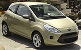 Ford Ka. Modelo 2009. Imagen exterior. Frontal lateral cenital. Coche parado. Carretera. Dorado.