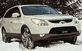 Hyundai ix55. Modelo 2009. Imagen. Exterior. Lateral frontal. Coche parado. Carretera con nieve. Luces faros en on. Color Vanilla White.