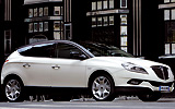 Lancia Delta. Modelo 2008. Imagen. Exterior. Lateral frontal. Coche parado. Carretera. Llantas aleaci&oacute;n 18 pulgadas. Techo solar el&eacute;ctrico. Color marfil luna piena.