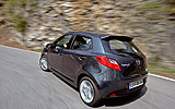 Mazda2. Modelo 2008. Kit deportivo. Imagen. Exterior. Lateral- posterior. Coche en movimiento. Carretera. Color Brilliant Black.