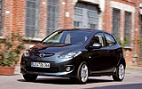 Mazda2. Modelo 2008. Kit deportivo. Imagen. Exterior. Frontal- lateral. Coche en movimiento. Carretera. Color Brilliant Black.