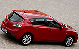 Mazda3. Modelo 2009. 5p Active 1.6 105 CV (con la opci�n pack active). Imagen. Exterior. Posterior lateral cenital. Coche parado. Carretera. Llantas de aleaci�n ligeras de dise�o de diez radios y 17 pulgadas. Color Velocity Red Mica.