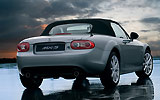 Mazda MX-5. Soft Top. Modelo 2009. Imagen exterior. Posterior- lateral. Coche parado. Techo de lona. Carretera. Gris.