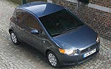 Mitsubishi Colt. Modelo 2009. 3 puertas. Imagen. Exterior. Lateral frontal cenital. Coche parado. Carretera.