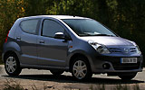 Nissan Pixo. Modelo 2009. Imagen. Exterior. Lateral frontal. Coche parado. Carretera.