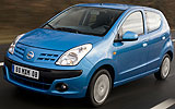 Nissan Pixo. Modelo 2009. Imagen. Exterior. Frontal lateral. Coche en movimiento. Carretera. Azul.