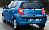 Nissan Pixo. Modelo 2009. Imagen. Exterior. Lateral posterior. Coche en movimiento. Carretera. Azul.
