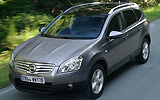 Nissan Qashqai+2. Modelo 2009. Imagen. Frontal- lateral. Coche en movimiento. Carretera. Gris.