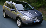 Nissan Qashqai+2. Modelo 2009. Imagen. Lateral- Frontal. Coche en movimiento. Carretera. Gris.