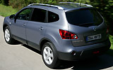 Nissan Qashqai+2. Modelo 2009. Imagen. Lateral- posterior. Coche en movimiento. Carretera. Gris.