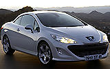 Peugeot 308 CC. Modelo 2009. Imagen. Exterior. Lateral frontal. Coche parado. Carretera. Techo r�gido plegable. Luces faros en on. Blanco brillante.