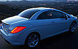 Peugeot 308 CC. Modelo 2009. Imagen. Exterior. Posterior lateral. Coche parado. Carretera. Techo r�gido plegable. Luces pilotos en on. Blanco brillante.