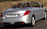 Peugeot 308 CC. Modelo 2009. Imagen. Exterior. Posterior lateral. Coche en movimiento. Carretera. Descapotado. Gris aluminio.