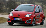 Renault Twingo RS. Modelo 2009. Imagen. Frontal lateral. Movimiento. Carretera. Luces faros en on. Rojo.