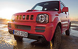 Suzuki Jimny. Modelo 2008. Imagen exterior. Frontal lateral. Coche parado. Carretera con agua. Rojo.
