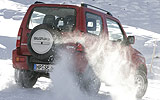 Suzuki Jimny. Modelo 2008. Imagen exterior. Posterior lateral. Coche parado. Carretera con nieve. Rojo.