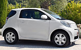 Toyota iQ. Modelo 2009. Imagen. Lateral. Coche parado. Carretera. Blanco.