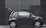 Toyota iQ. Modelo 2009. Imagen. Lateral. Coche parado. Carretera. Port�n maletero abierto. Negro.