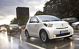 Toyota iQ. Modelo 2009. Imagen. Lateral frontal. Movimiento. Coche en carretera. Blanco.