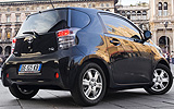 Toyota iQ. Modelo 2009. Imagen exterior. Lateral posterior. Coche parado. Carretera. Negro.