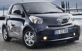 Toyota iQ. Modelo 2009. Imagen exterior. Frontal lateral. Coche parado. Carretera. Negro.