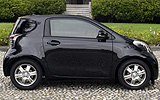 Toyota iQ. Modelo 2009. Imagen exterior. Lateral. Coche parado. Carretera. Negro.