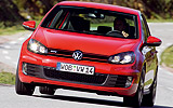 Volkswagen Golf GTI. Modelo 2009. 5 puertas. Imagen. Exterior. Frontal. Coche en movimiento. Carretera. Luces faros encendidos. Rojo.