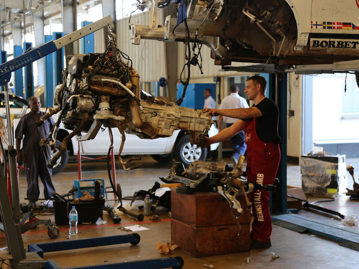 Pese a ir en posición longitudinal, la mecánica resultó ilesa. Obsérvese el enorme tamaño de la transmisión respecto al del motor V6; y eso que el diferencial delantero, que irá situado casi bajo el cárter, está sobre las cajas de madera.