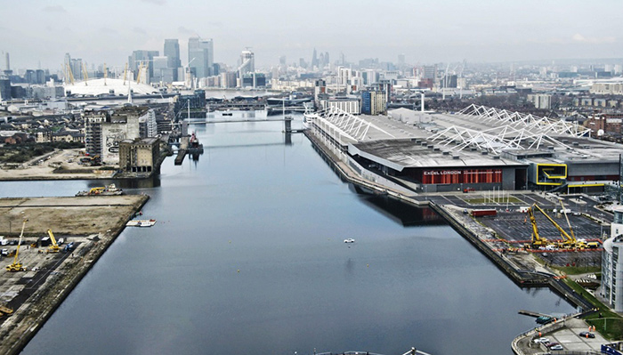 En la dársena de Canary Wharf (London Business District) el Jaguar XF aparece como un diminuto punto blanco colgado sobre el agua, a mitad de su recorrido. A uno y otro lado, las grúas que sujetan el conjunto de cables.