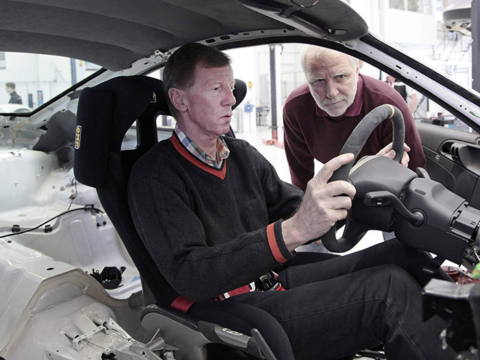 El legendario Walter Röhrl (¡maldición!: siete años más joven que yo, semana arriba o abajo) analiza la postura de conducción de un 911 GT3 RS limpio de guarnecidos, pero bastante menos radical que el GT-1 de Le Mans de una foto anterior, con Mark Webber al volante.