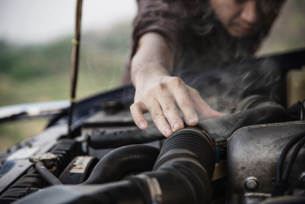 Conductor revisando el humo que sale de su motor por un mal hábito