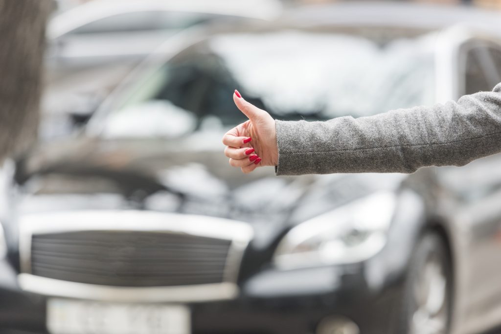 Conductor levantando el pulgar ante un coche con el seguro adecuado